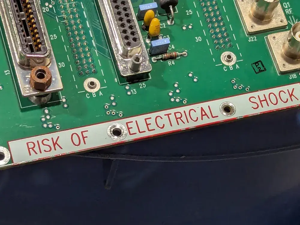 "RISK OF ELECTRICAL SHOCK" in red silkscreen overprinted on top of a band of white silkscreen.