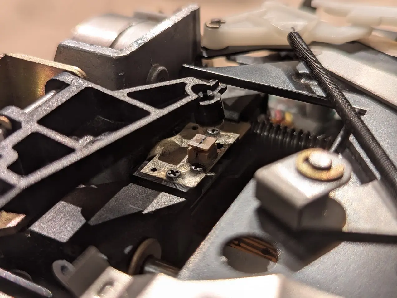 rectangular read/write head perched on the sled assembly, with the pressure pad arm poised above it.